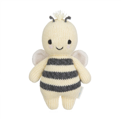 The Cuddle + Kind Bee - Baby 7" is a handcrafted, knitted plush toy featuring black and white stripes, small wings, a smiling face, and short antennae—an heirloom-quality addition to any hand-knit baby animals collection.