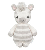 Introducing the Zebra - Baby 7" by Cuddle + Kind, a hand-knit baby animal crafted from heirloom-quality Peruvian cotton yarn. This plush toy showcases gray and white stripes, small ears, black eyes, a smiling mouth, and a tuft of yarn hair on top—making it a charming keepsake to treasure for years to come.