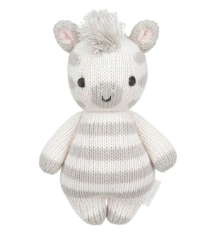 Introducing the Zebra - Baby 7" by Cuddle + Kind, a hand-knit baby animal crafted from heirloom-quality Peruvian cotton yarn. This plush toy showcases gray and white stripes, small ears, black eyes, a smiling mouth, and a tuft of yarn hair on top—making it a charming keepsake to treasure for years to come.