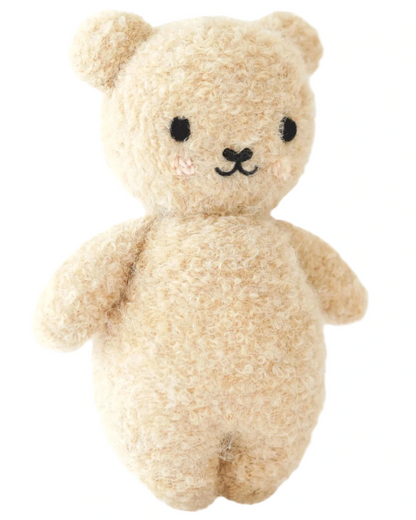 The Baby Boucle Bear - Honey by Cuddle + Kind is a beige, textured plush teddy crafted from heirloom-quality Peruvian cotton yarn, with black eyes, a stitched nose and mouth, and softly blushed cheeks.