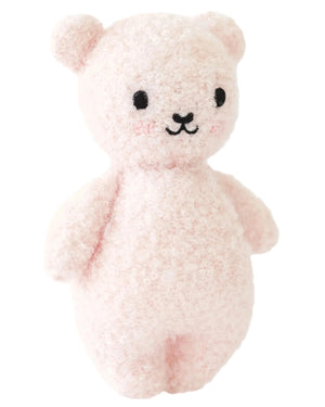 The Baby Boucle Bear - Strawberry by Cuddle + Kind is a pale pink plush teddy crafted from heirloom-quality Peruvian cotton yarn, with black embroidered eyes and nose, rounded ears, and a minimalist design.