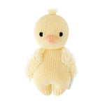 The Baby Duckling by Cuddle + Kind is a handcrafted plush chick toy, made from Peruvian cotton yarn and featuring black eyes, a peach beak, and textured wings in a cheerful yellow hue. Inspired by classic heirloom baby animals, it is displayed against a white background.