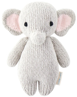 The Baby Elephant by Cuddle + Kind is a hand-knit plush toy crafted from heirloom-quality Peruvian cotton yarn, featuring large ears, black eyes, and a soft texture. Shown on a plain white background.