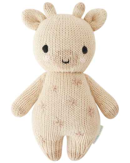The Baby Giraffe by Cuddle + Kind is a beige knitted plush giraffe made from heirloom-quality Peruvian cotton yarn, with stitched facial details, small horns, and a cheerful smile.