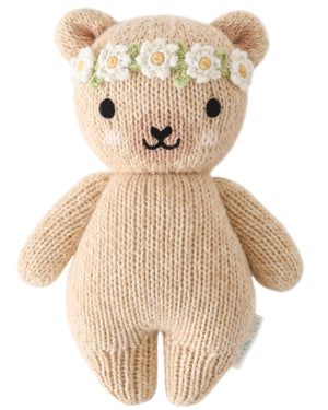 The Baby Honey Bear Ivory Floral by Cuddle + Kind is an heirloom-quality, knitted teddy bear with a white and yellow daisy flower crown—a charming addition to any hand-knit baby animals collection.