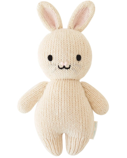 The Baby Rabbit - Oatmeal by Cuddle + Kind is a hand-knit, cream-colored stuffed bunny with black eyes, stitched nose and mouth, and upright ears—an heirloom-quality doll perfect for little animal lovers.
