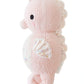 The Baby Seahorse - Powder Pink by Cuddle + Kind is an heirloom-quality plush toy crafted from soft Peruvian cotton yarn, featuring a white fin and tail, black stitched eye, and a small side tag.
