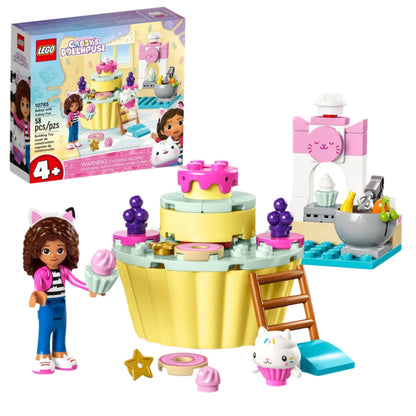 Introducing the LEGO® Bakey with Cakey Fun building toy set from Legos - Toyhouse! This delightful set features a character with brown hair holding a cupcake, a tiered cake structure complete with a ladder, an adorable cat figure, and a stand mixer. The set box in the background adds to the fun. Dive into creative construction and enjoy endless baking adventures!