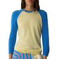 A person wearing the Guest in Residence Baseball Tee, a cream-colored women's cashmere sweater with blue colorblock raglan sleeves, accessorized with a beaded necklace and a striped garment tied at the waist.