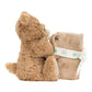 A Jellycat Bartholomew Bear Soother features a brown teddy bear sitting with a rolled-up beige blanket tied with a ribbon, embodying the cozy charm of Jellycat.