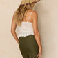 A woman stands with her back to the camera, wearing the Lorna Murray Luxe Beauty Point Hat—a UPF 50+ straw travel hat—paired with a white lace top and a high-waisted olive green skirt featuring a back slit.