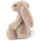 The Jellycat Bashful Beige Bunny, Small, is a plush light brown bunny with long floppy ears, black eyes, a pink nose, and a white fluffy tail—an adorable gift for any occasion.