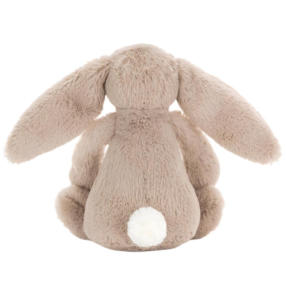 The Jellycat Bashful Beige Bunny, Small, sits facing away with long floppy ears and a white tail—a charming plush gift.