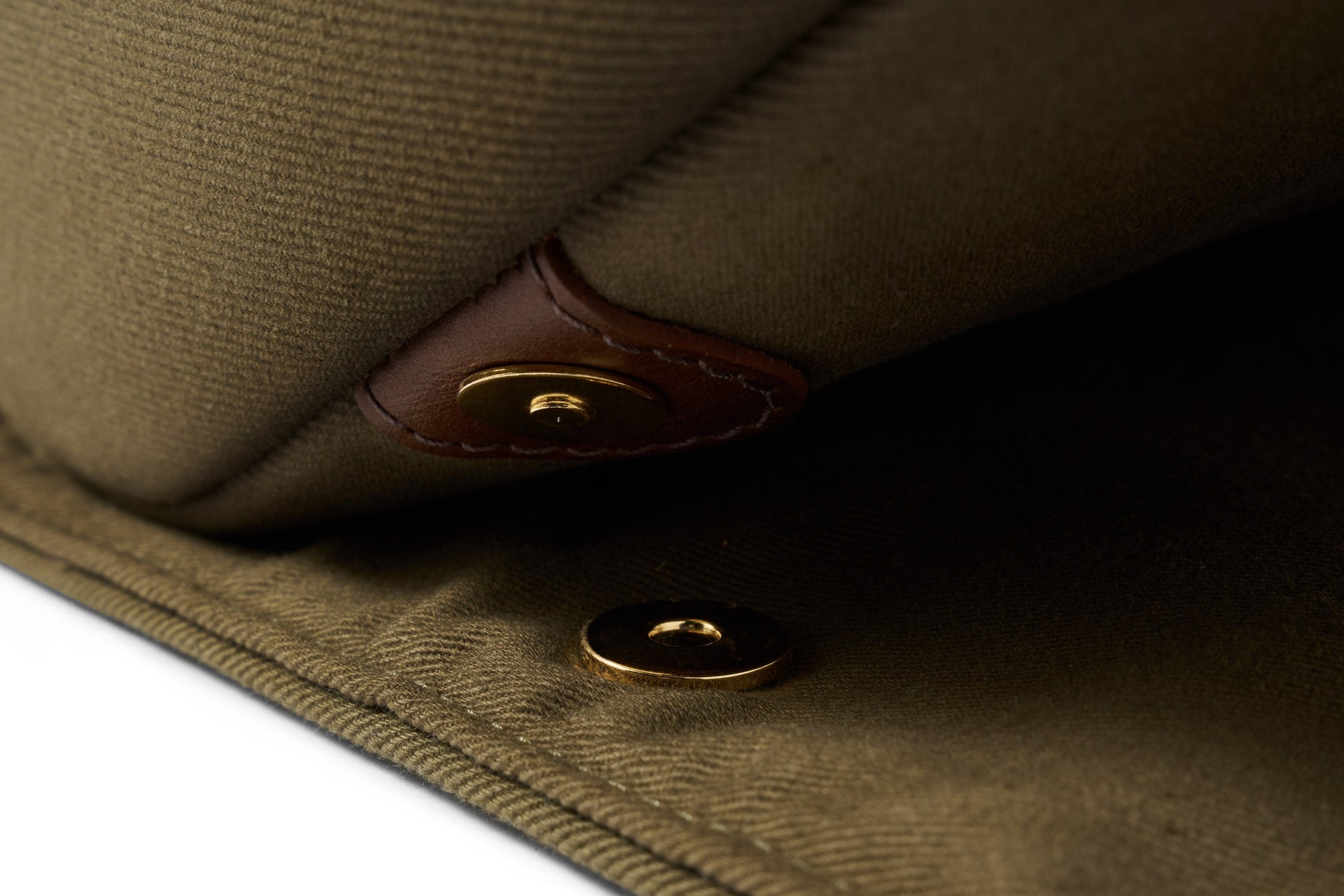 Close-up of the Bennett Winch S.C Holdall, designed with khaki waterproof canvas, a magnetic button closure, and leather trim detail.