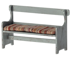 The Maileg Bench, Mouse by Maileg is a small, rustic wooden bench with a distressed finish and a cushioned seat covered in striped fabric—perfect for adding a touch of Mouse Hole Farmhouse charm to your decor.