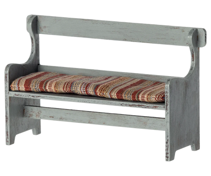 The Maileg Bench, Mouse by Maileg is a small, rustic wooden bench with a distressed finish and a cushioned seat covered in striped fabric—perfect for adding a touch of Mouse Hole Farmhouse charm to your decor.