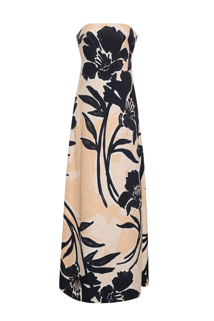 The Benita Dress by Cara Cara is a strapless, beige stretch crepe gown with a placed black floral print and an elegant A-line silhouette.