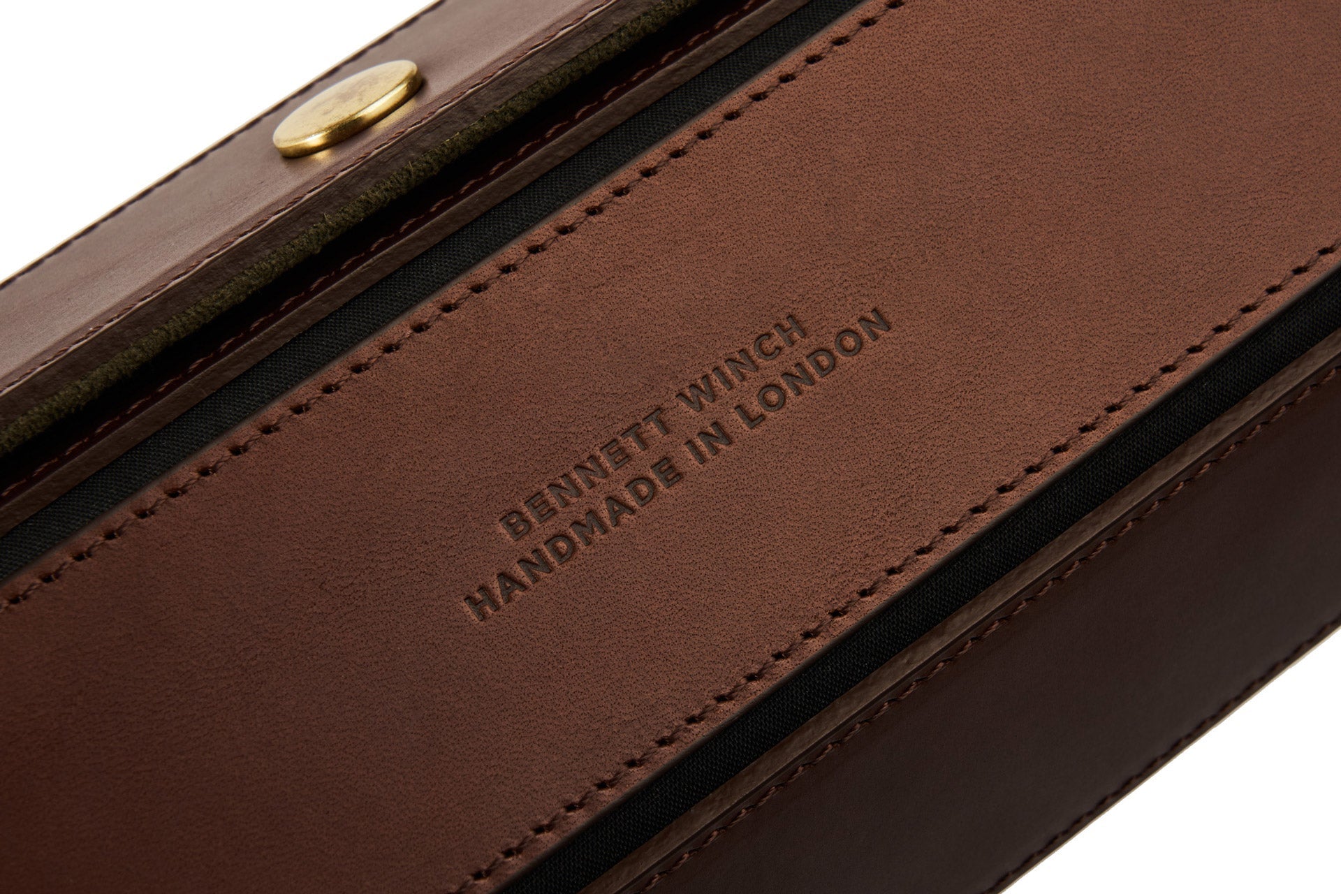 Close-up of a brown leather watch roll, identified as the Bennett Winch Triple Watch Roll, crafted with Tuscan leather panels and embossed with "Bennett Winch Handmade in London," featuring a visible gold button.