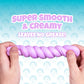 Two hands stretch a twisted, pastel purple, clay-like substance—Better Butter - Berry Thinking Putty by Crazy Aaron’s—perfect for sensory play. Text above reads, “Super smooth & creamy. Leaves no grease!” Cartoon faces make up the playful background pattern, while a hint of berry scent makes this putty extra delightful.