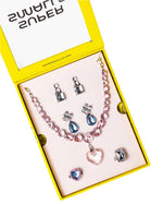 The Super Smalls Big Presentation Jewelry Set features a yellow box with a pink beaded heart necklace, three earring pairs, and two adjustable rings decorated with pink, blue, and silver stones for pastel elegance.