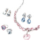 The Super Smalls Big Presentation Jewelry Set features pastel elegance with a pink gemstone necklace, blue gemstone earrings, and a pink-and-blue ring, all displayed beautifully on a white background.