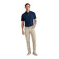 A man faces forward wearing the Peter Millar Bingham Performance Five-Pocket Pant in beige, a navy blue wrinkle-resistant Italian knit polo shirt, and light gray sneakers against a white background.