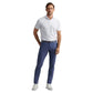 A man stands facing forward against a white background, wearing Peter Millar Bingham Performance Five-Pocket Pant in blue, a wrinkle-resistant white Italian knit polo, a black belt, and white sneakers.