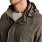 A person wearing the Peter Millar Discovery Field Jacket with a hood and a white sweater underneath.