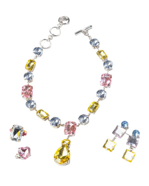 The Super Smalls Black Tie Mega Set, featuring a necklace with blue, yellow, and pink supersized gemstones, two pairs of gemstone earrings, and two adjustable rings, is displayed on a white background.
