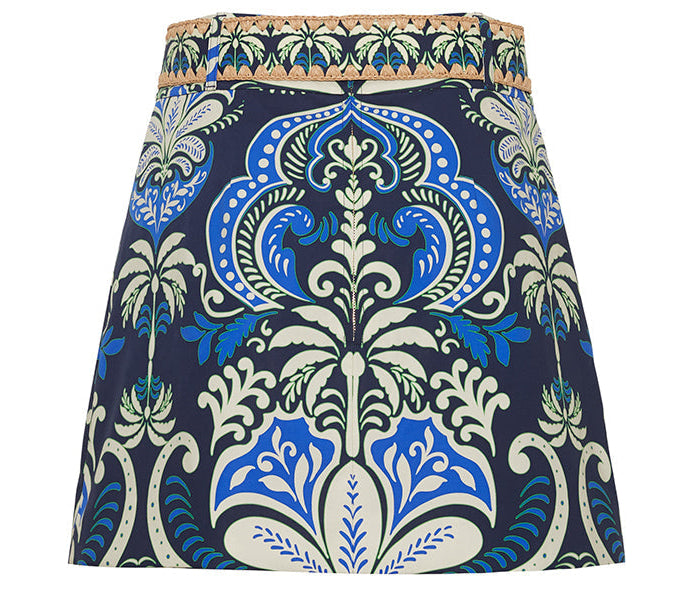 The Blaze Skirt by Cara Cara showcases a chic blue, white, and green floral A-line design with a woven tan raffia belt waistband.