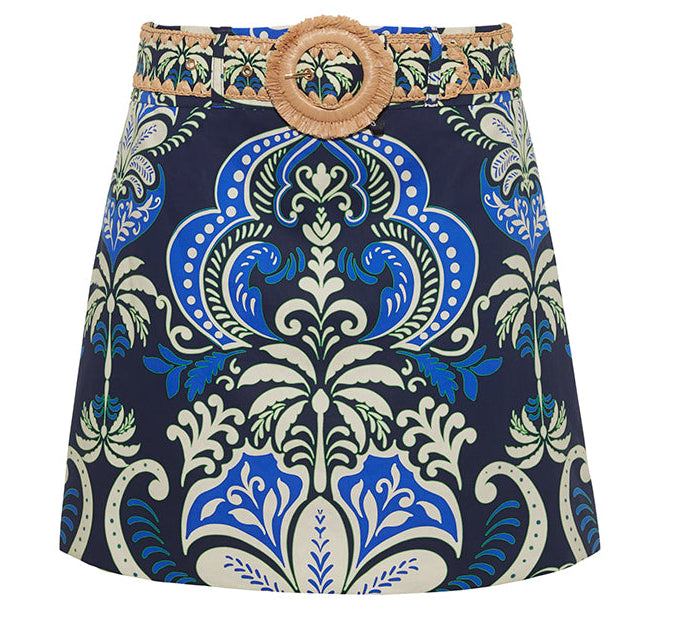 The Blaze Skirt by Cara Cara is a chic A-line mini with a bold blue, green, and cream baroque print, finished with a raffia belt and round buckle.