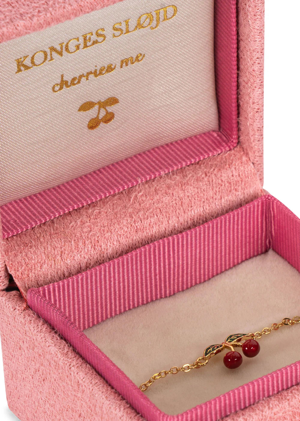 This pink velvet box contains a 24K gold-plated cherry bracelet by Konges Sløjd, perfect for special occasions. The lid elegantly displays "Konges Sløjd cherries me," making it an enchanting surprise for any cherished moment.