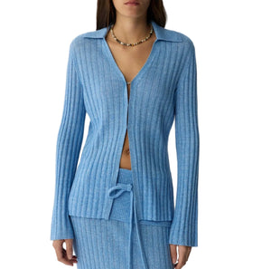 A woman styles the Guest in Residence Breezy Cardigan and matching skirt with a tie waist, accented by a beaded necklace—ideal for effortless spring and summer outfits.