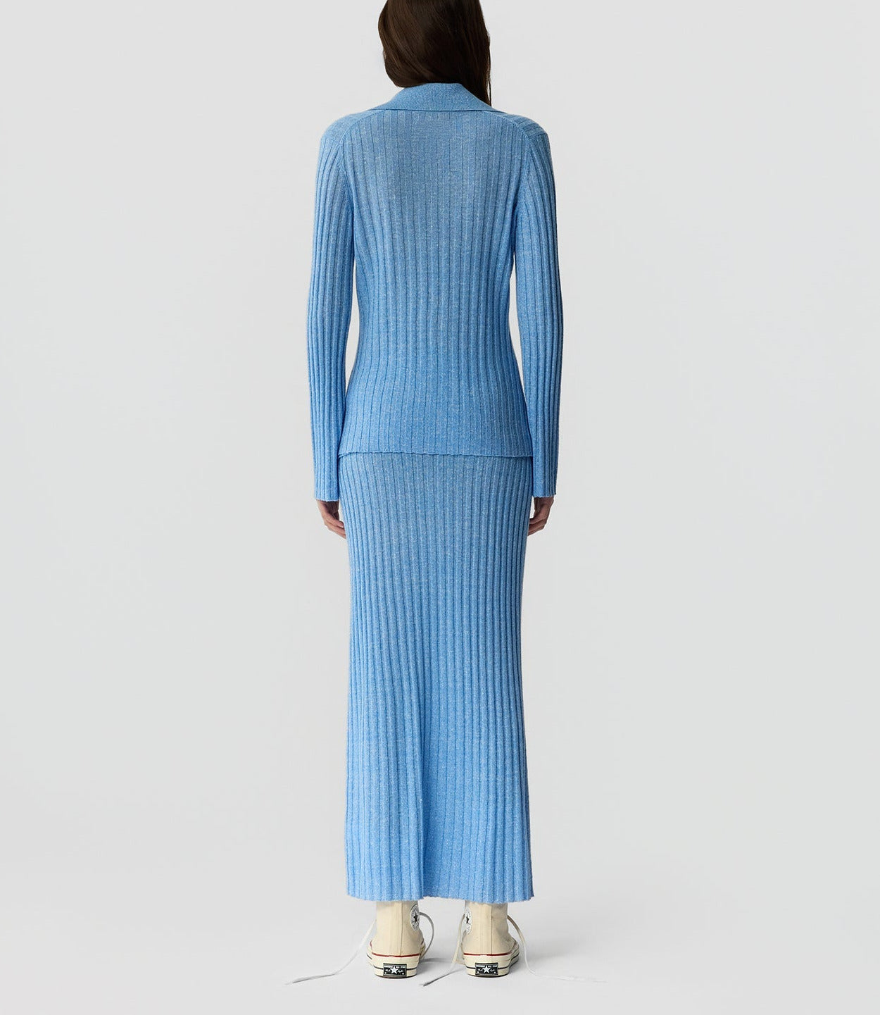 A person faces away from the camera, wearing the Guest in Residence Breezy Cardigan in blue with a matching ankle-length skirt and white sneakers against a plain backdrop, showcasing effortless spring-summer style.