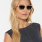 A woman with long blonde hair wears Krewe’s Brigitte Sunglasses—lightweight acetate cat-eye frames—paired with a textured dark sleeveless top with scalloped edges, posed against a plain white background.