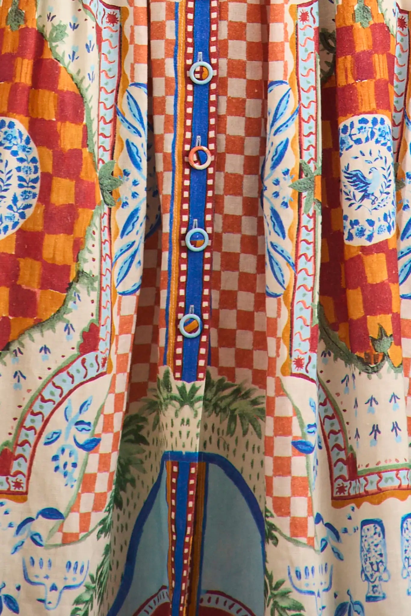 Close-up of the Eva Skirt by Hunter Bell NYC, showcasing a checkered pattern, blue buttons, and an intricate sundance tile print in red, orange, blue, and green on a soft linen-rayon blend.