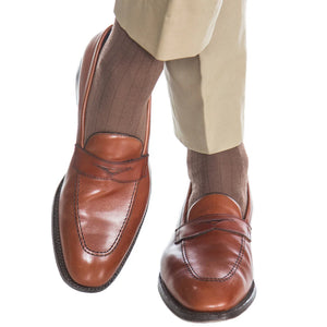 A person wearing light brown dress pants, Dapper Classics Mushroom Solid Ribbed Fine Merino Wool Sock Linked Toe Mid-Calf, and brown leather loafers.