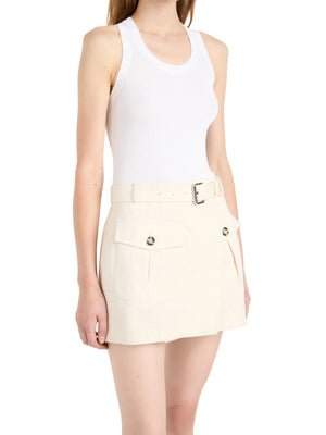 A woman wearing a white sleeveless tank top and the Bruni Short by Proenza Schouler—cream high-rise shorts featuring a belted waist, front flap pockets, and button details—standing against a plain background.