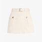 The Bruni Short by Proenza Schouler is a beige A-line mini skirt featuring front flap pockets, button details, and a matching belt with a silver buckle. Crafted from durable and structured cotton drill, it offers a chic alternative to classic high-rise shorts for any modern wardrobe. Displayed against a plain white background.