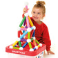 A young child in a red shirt sits beside a bin labeled "SMARTMAX," building colorful structures with SmartMax Build XXL magnetic rods and balls from Smart Games.