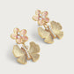 The Anabel Aram Butterfly with Enamel Flower Earrings feature a pink enamel flower, clear stones, and a butterfly-shaped lower design accented with small crystals in a gold-toned setting.