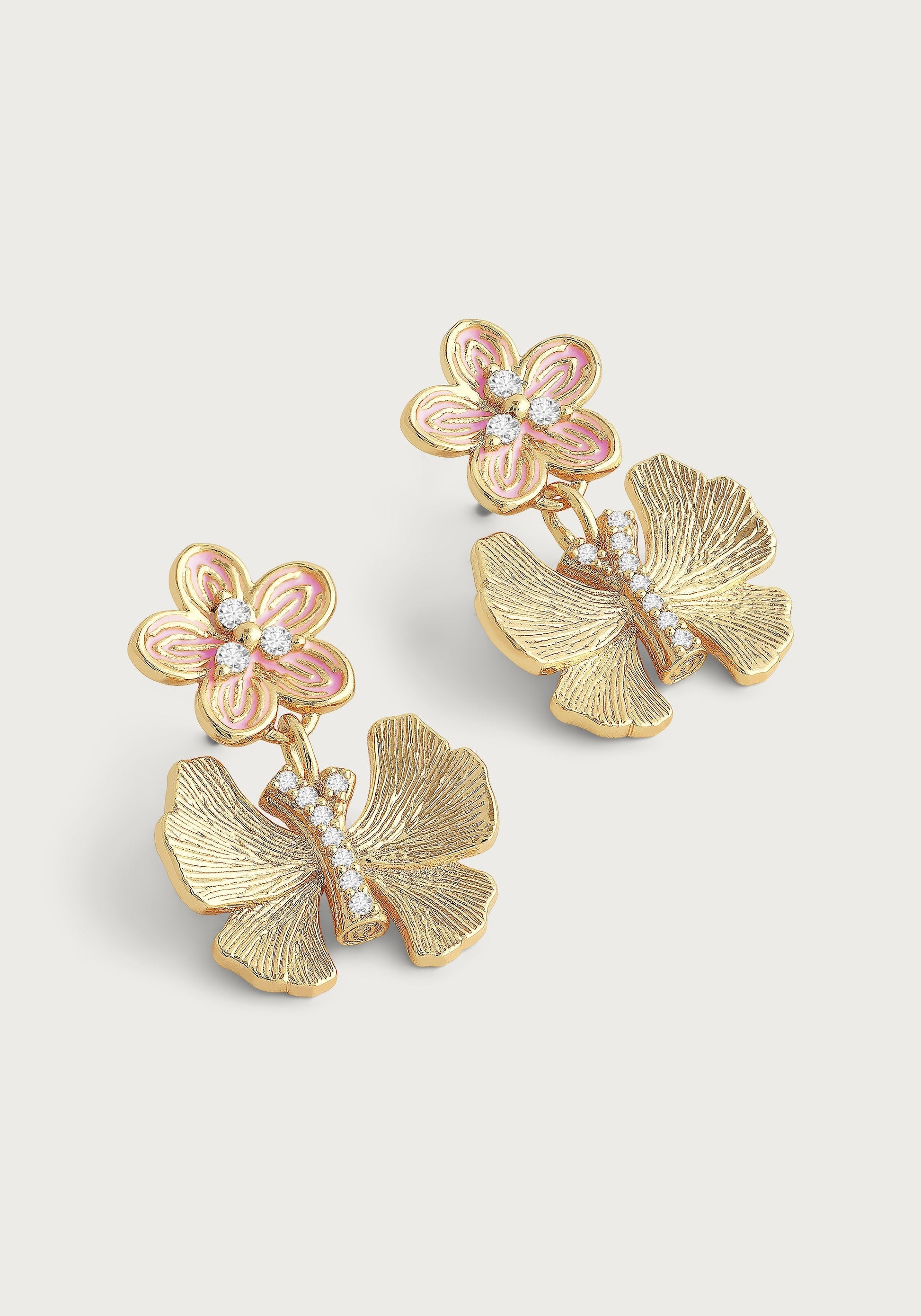 The Anabel Aram Butterfly with Enamel Flower Earrings feature a pink enamel flower, clear stones, and a butterfly-shaped lower design accented with small crystals in a gold-toned setting.