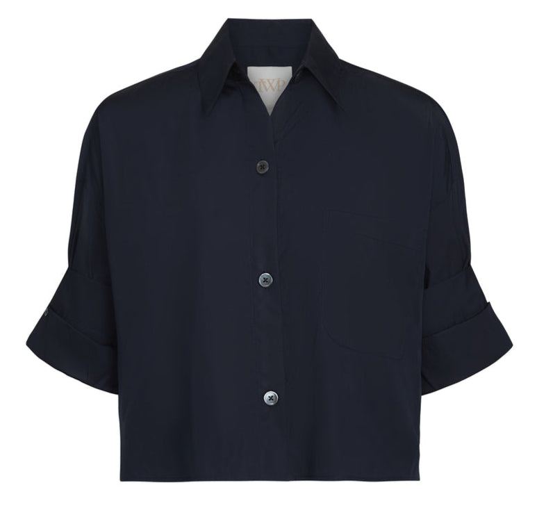 The Next Ex Shirt by TWP is a short-sleeved, dark navy button-up with a collar and chest pocket, made from vintage washed poplin in a relaxed boxy fit, showcasing three visible front buttons.