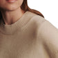A close-up image of a person wearing a TWP Boy Cashmere Crew, focusing on the textured fabric near the neck and shoulder area. The person's face is partially visible.