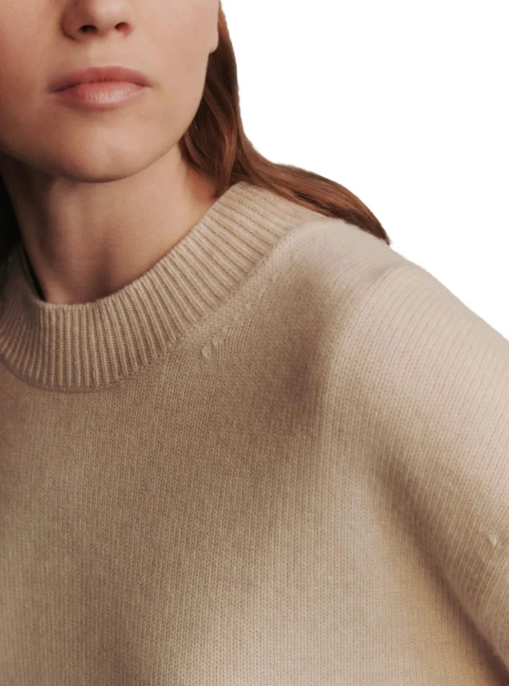 A close-up image of a person wearing a TWP Boy Cashmere Crew, focusing on the textured fabric near the neck and shoulder area. The person's face is partially visible.