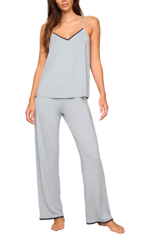 A woman models the Eberjey Frida Cami & Pant PJ Set, featuring a light gray sleeveless camisole and wide-leg pants with black trim, all crafted from buttery soft fabric.