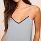A woman wears the Eberjey Frida Cami & Pant PJ Set featuring a light blue V-neck spaghetti strap top with dark trim, made from buttery soft TENCEL Modal for exceptional comfort.