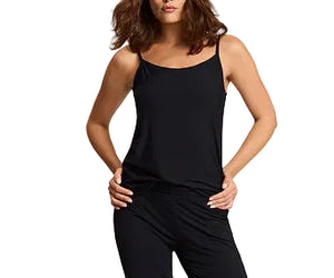 A woman stands with her hands on her hips wearing a Commando Butter Cami in black with adjustable straps and matching black pants.
