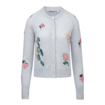 The Clemence Clematis Intarsia Cardigan by Bernadette features a soft wool knit in light blue-grey with a round neck, front buttons, and pink floral patterns, shown against a white background.