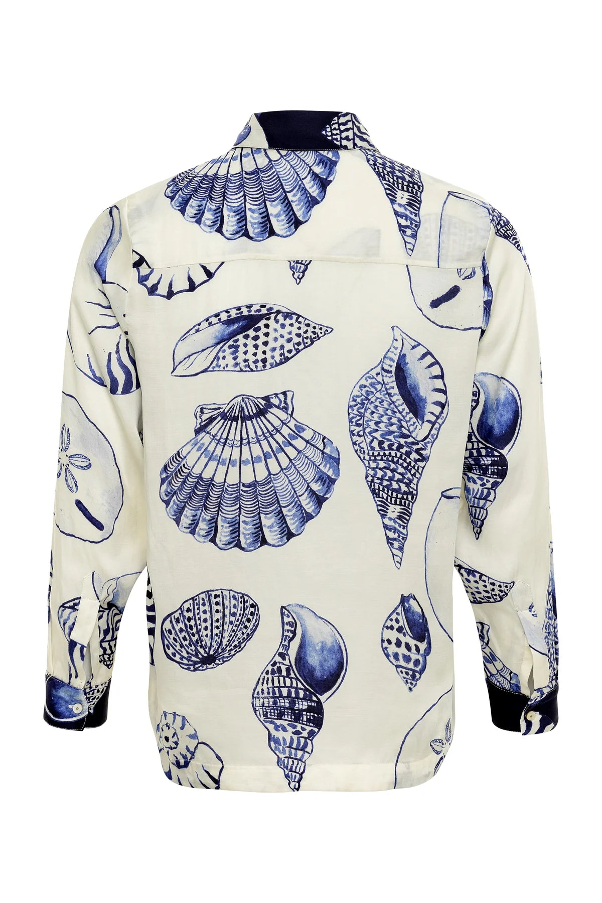 The Carmen Shirt by Carolina K is a long-sleeve top with blue seashells on a white background, seen from the back, inspired by a South African artist collaboration.